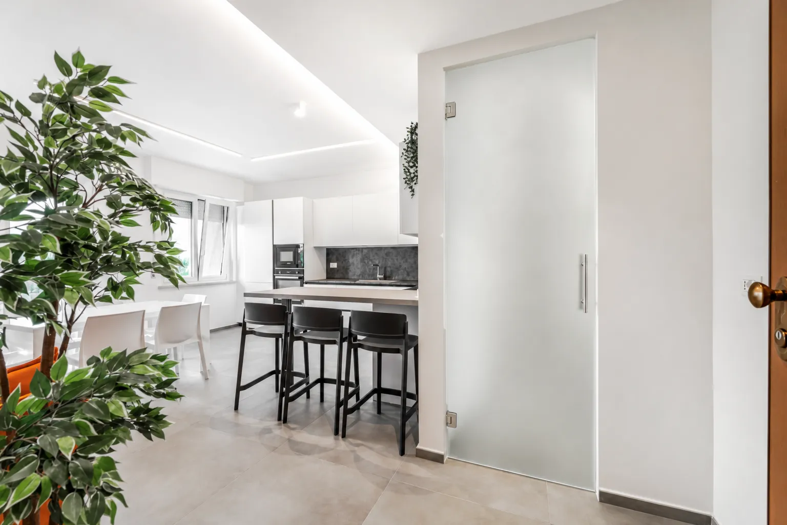 Ingresso con porta scorrevole in vetro verso la cucina di un appartamento ristrutturato